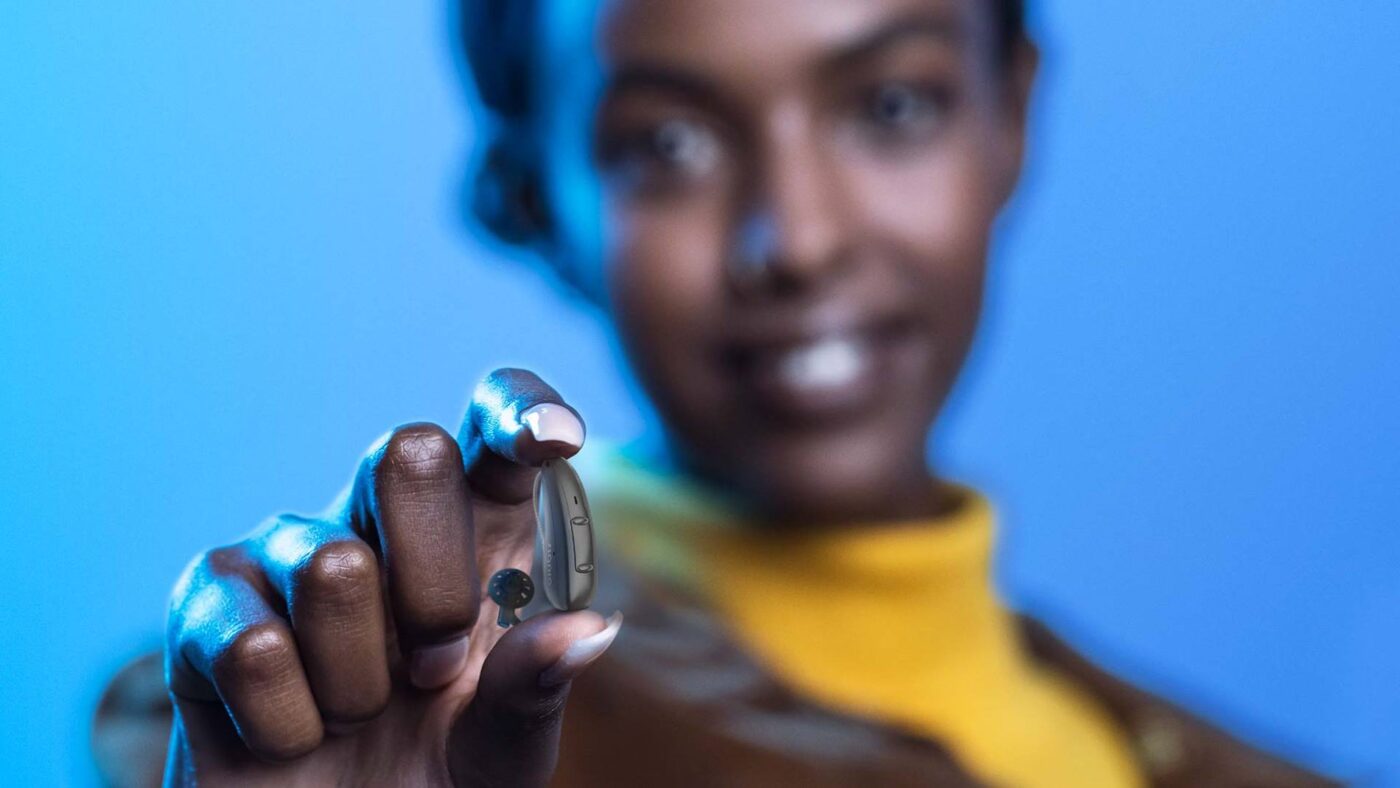 Pure-Charge-Go-AX_young-woman_holding-hearing-aid