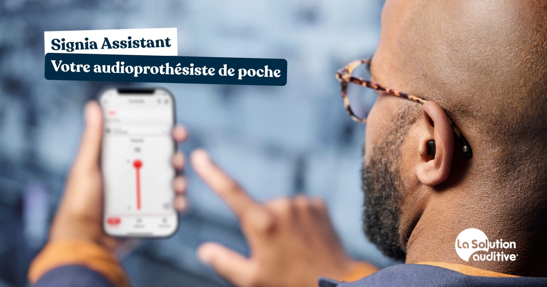 un homme équipé d'aides auditives regarde son smarthphone et son Signia assistant